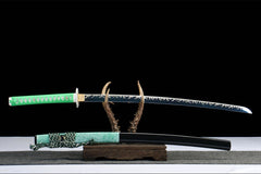 Detailed view of 惊蛰 drawn beside the gloss black saya and dark braided sageo