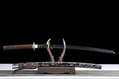 Fenchengjie Katana resting on antler stand with matching black silver pattern scabbard