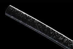 Textured close-up of 破阵子 saya under light with its dark sea-like speckled surface